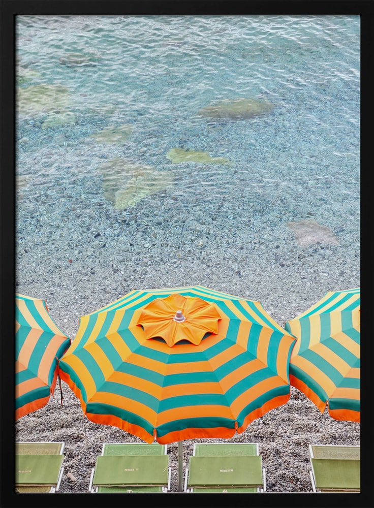 Luftaufnahme eines orange-grün gestreiften Sonnenschirms am Kiesstrand mit türkisem Wasser