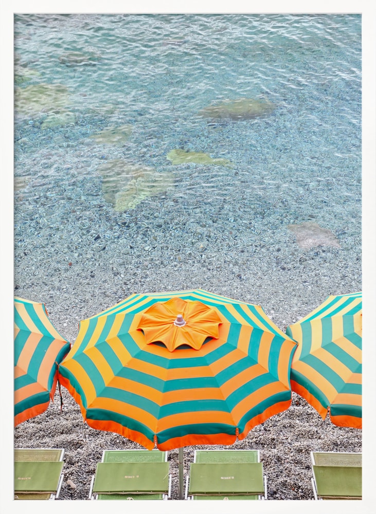 Luftaufnahme eines orange-grün gestreiften Sonnenschirms am Kiesstrand mit türkisem Wasser