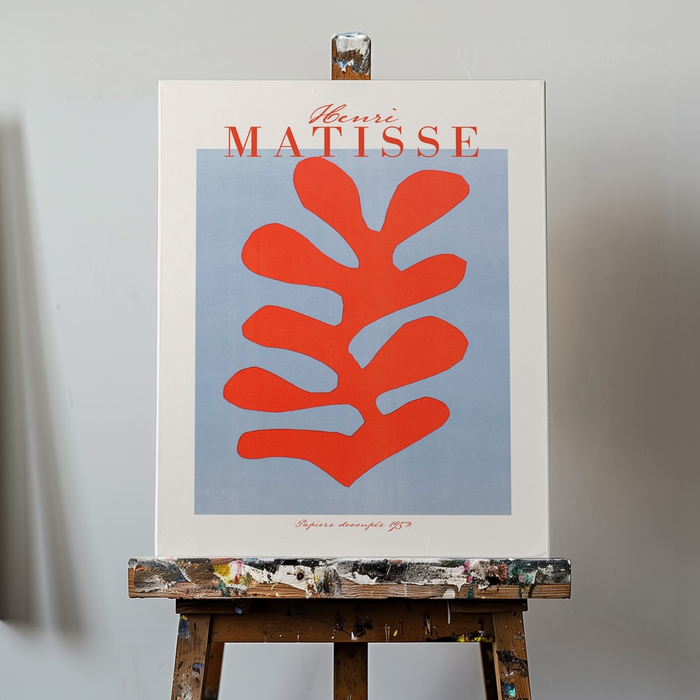Ausstellungsplakat Henri Matisse mit korallenrotem Scherenschnitt-Blatt auf hellblauem Grund, roter Schriftzug