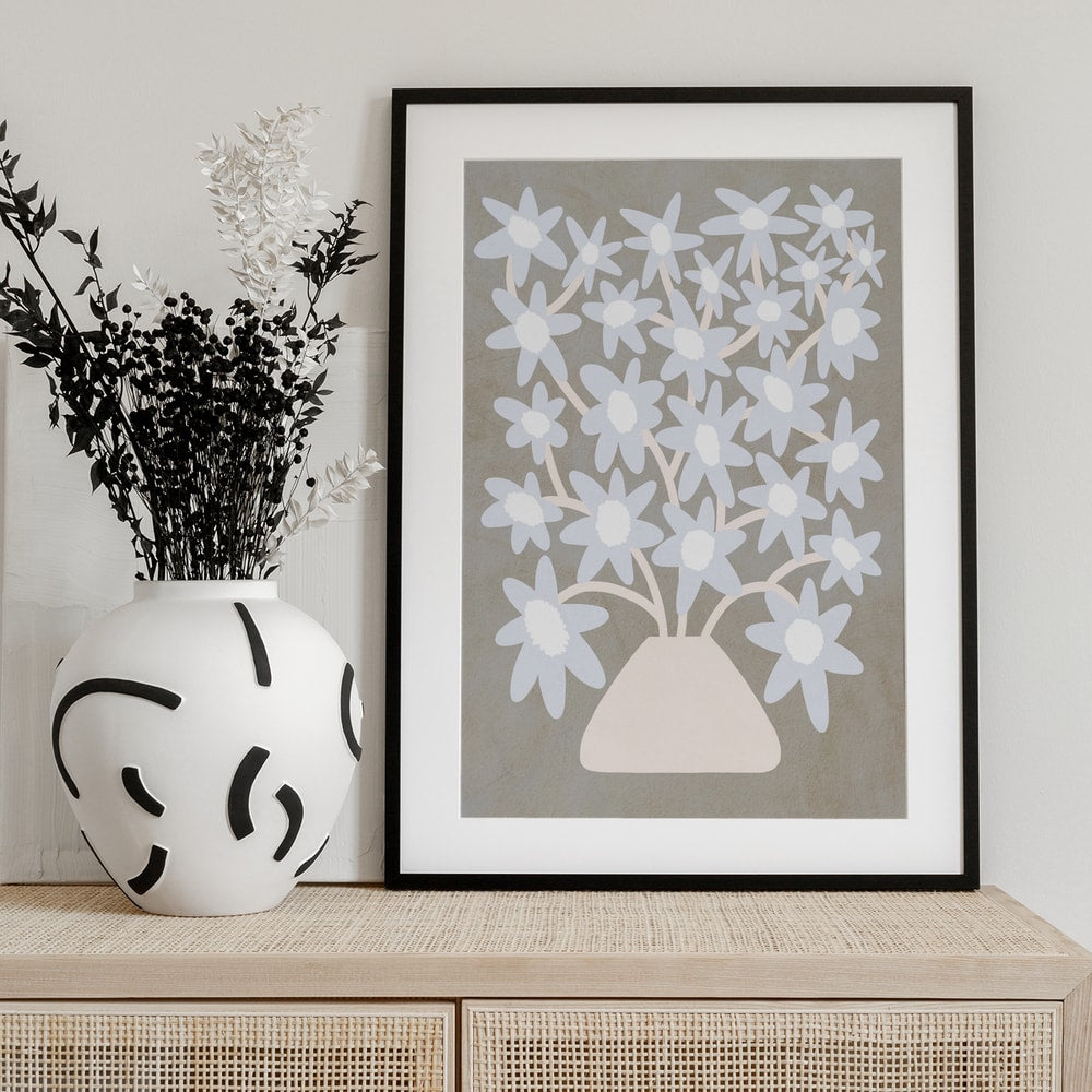 Stilisierter Strauß hellblauer Blüten in einer cremefarbenen Vase auf grauem Hintergrund