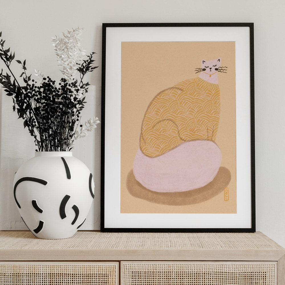 Illustration einer runden Katze im gelb gemusterten Pullover auf rosa Kissen