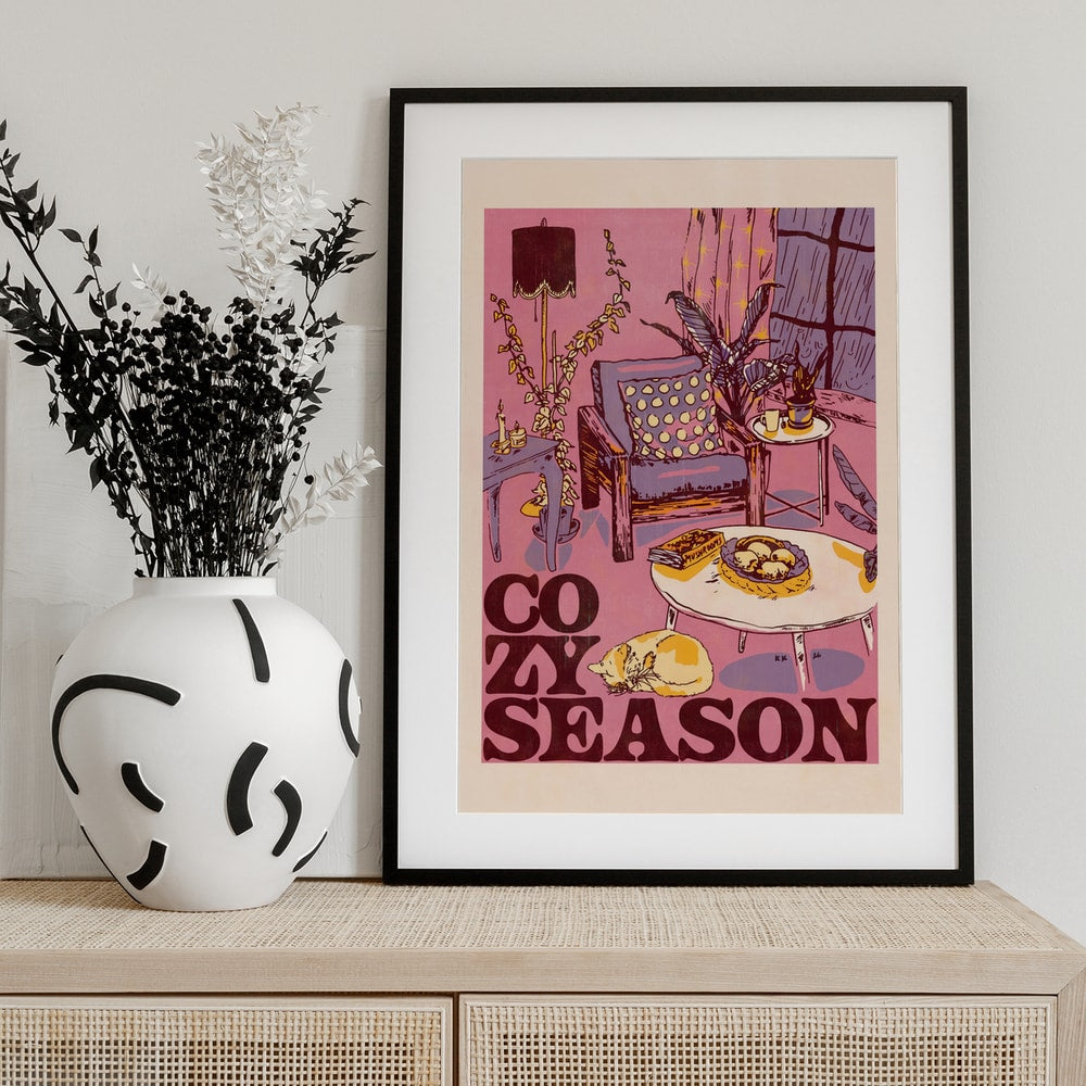 Illustration eines gemütlichen Wohnzimmers mit Sessel, Pflanzen und schlafender Katze, Schriftzug Cozy Season