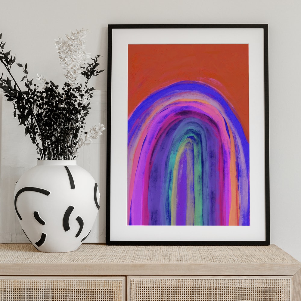 Gemalter Regenbogen in Violett, Pink, Blau und Gelb vor orangem Hintergrund
