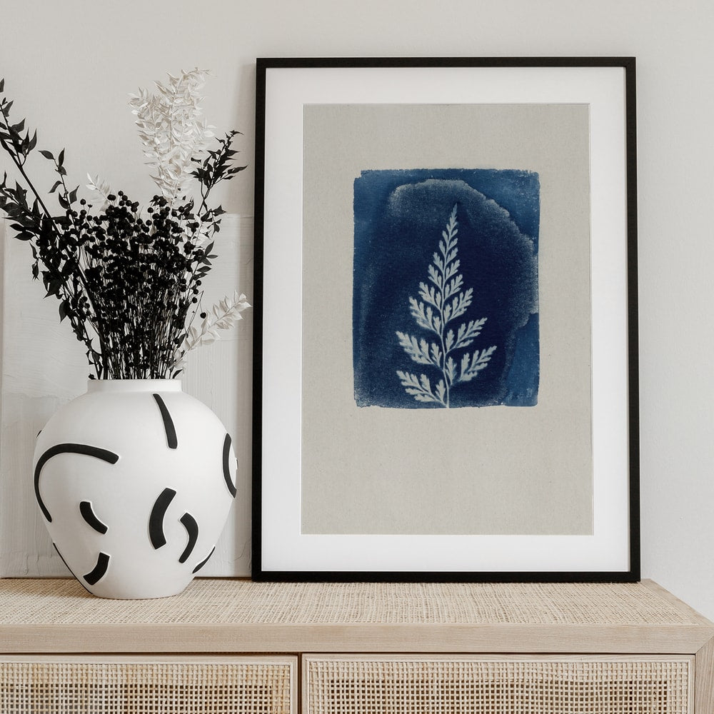 Weißes Farnblatt auf blauem Quadrat im Cyanotypie-Stil auf hellem Papier
